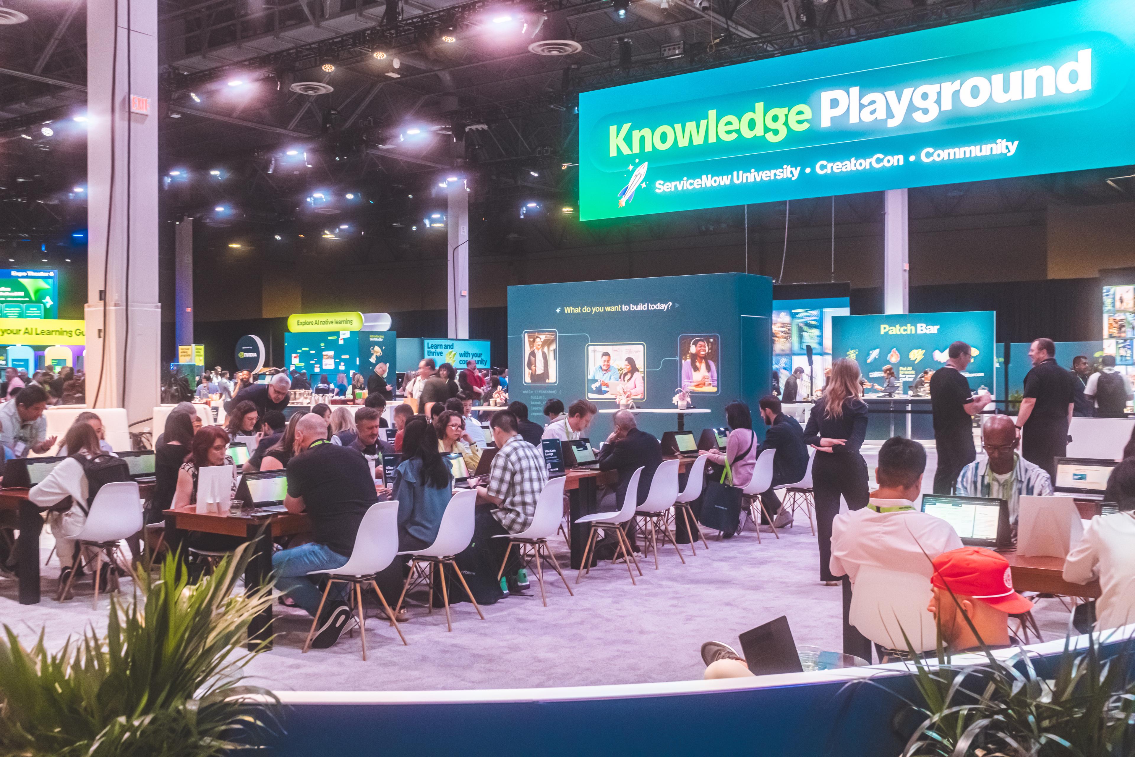 Packed Knowledge Playground area at a ServiceNow conference — attendees at tables with laptops under blue LED signage